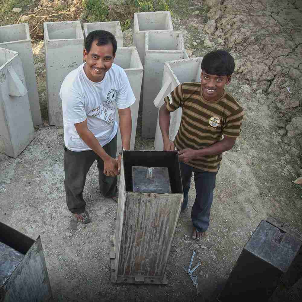 Two men showing the construction of a BioSand Water Filter