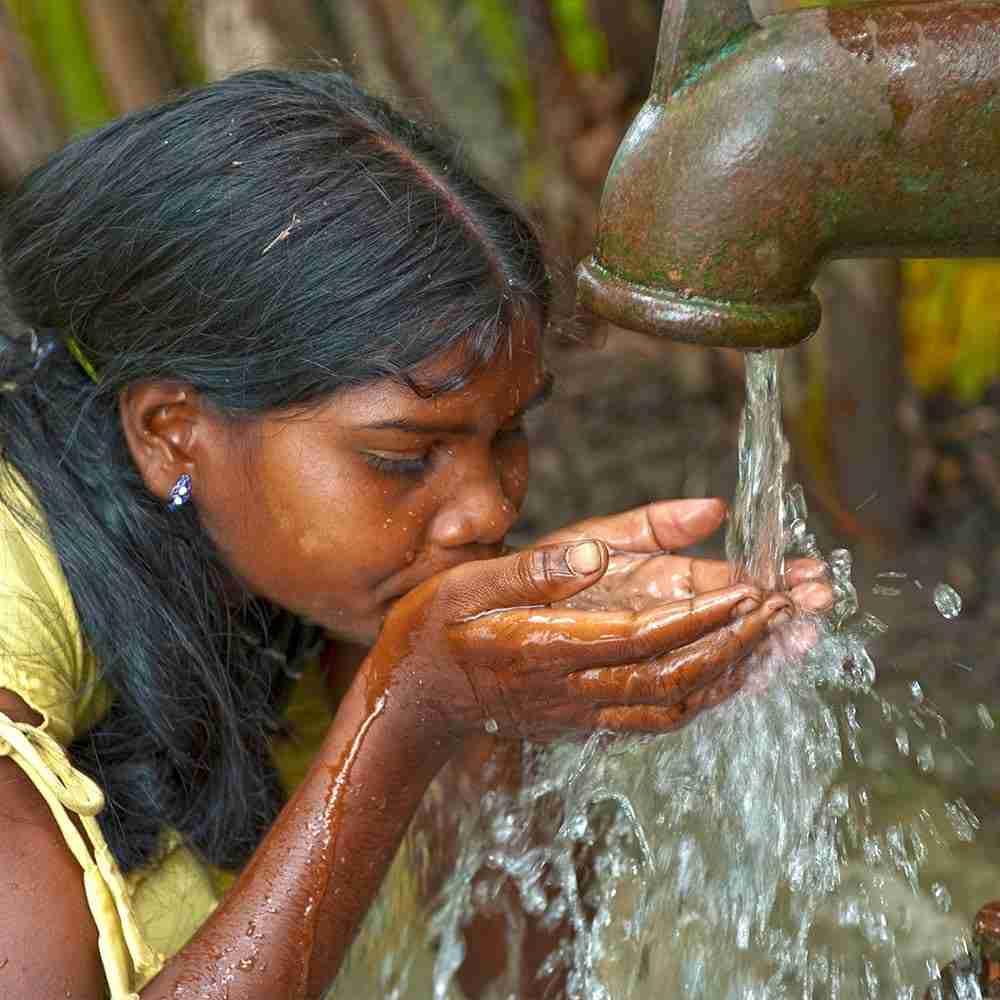 A woman drinking clean water directly from GFA Jesus Wells