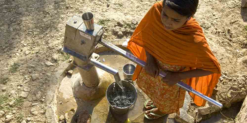 Woman drawing clean water through GFA World charity Jesus Wells