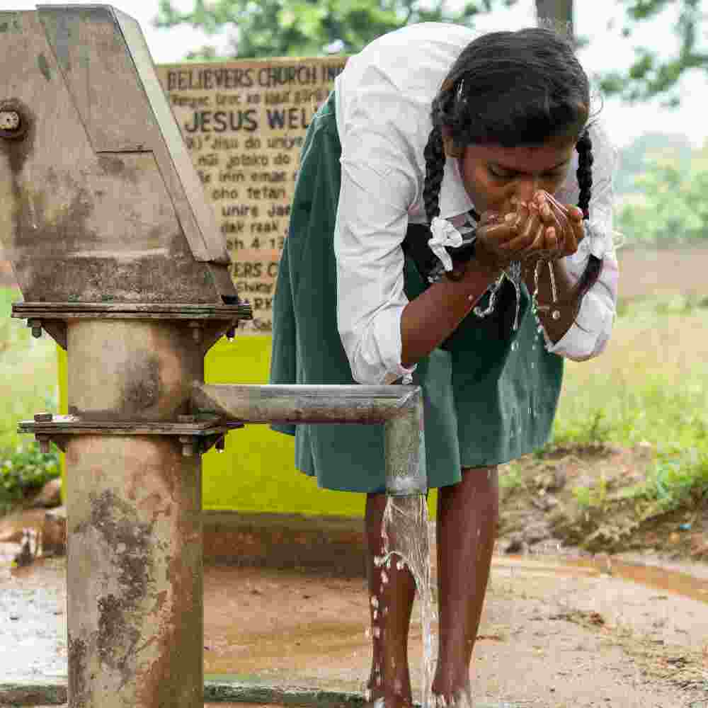 Young girl drinking clean water from GFA World Jesus Wells, a water crisis solution