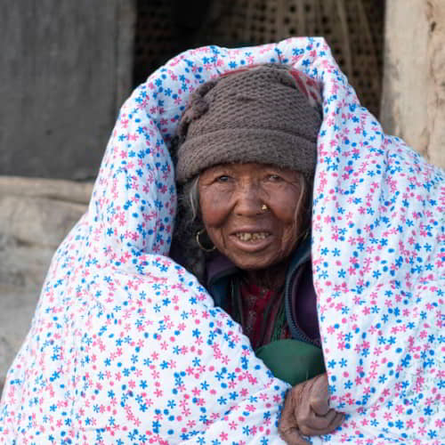 Elderly woman in poverty from Nepal received a warm blanket through GFA World gift distribution