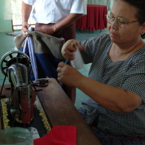 Women learn to use a sewing machine through GFA World vocational training