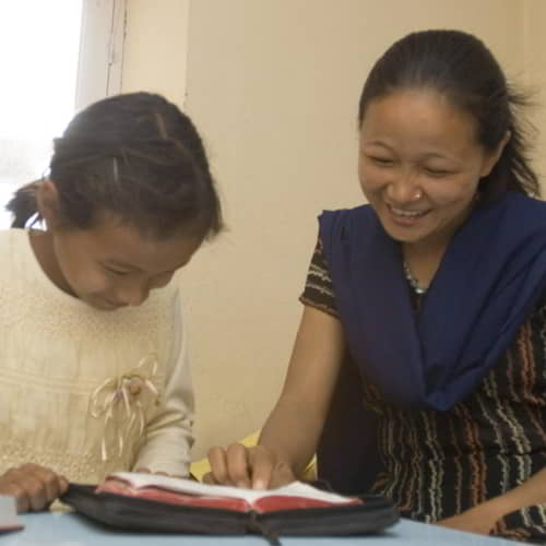 GFA World woman missionary in Nepal teaching her daughter to read the Bible