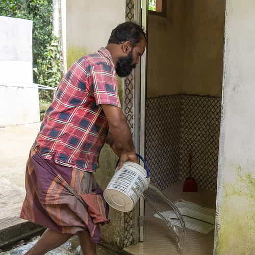 Man cleaning GFA World outdoor toilet