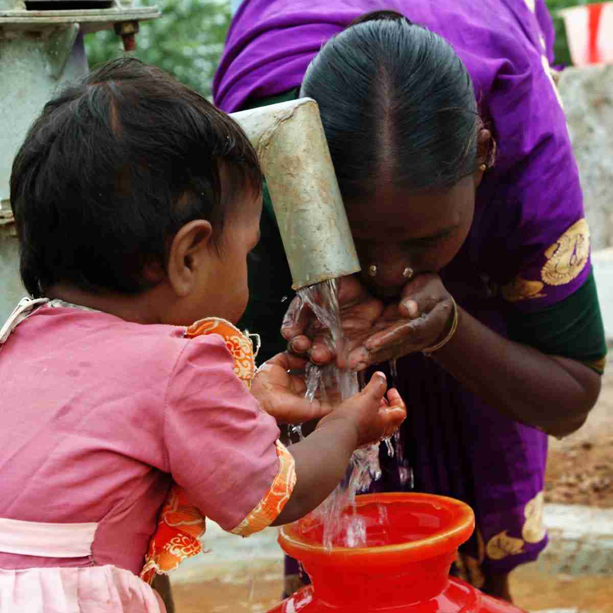 Mother and child enjoys drinking clean water from Jesus Wells