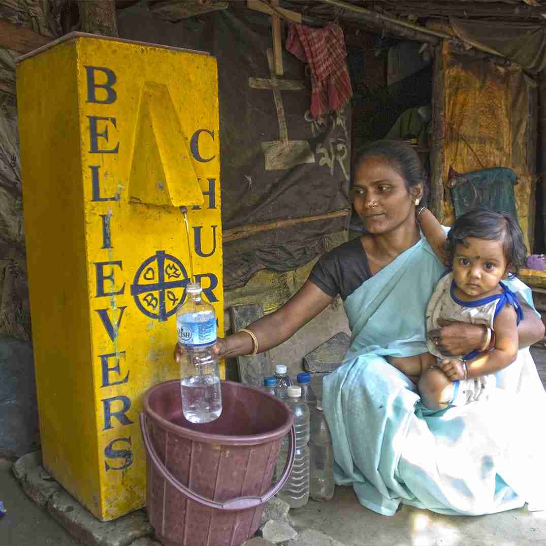 Mother with child, filling up bottles with clean water from BioSand Water Filter
