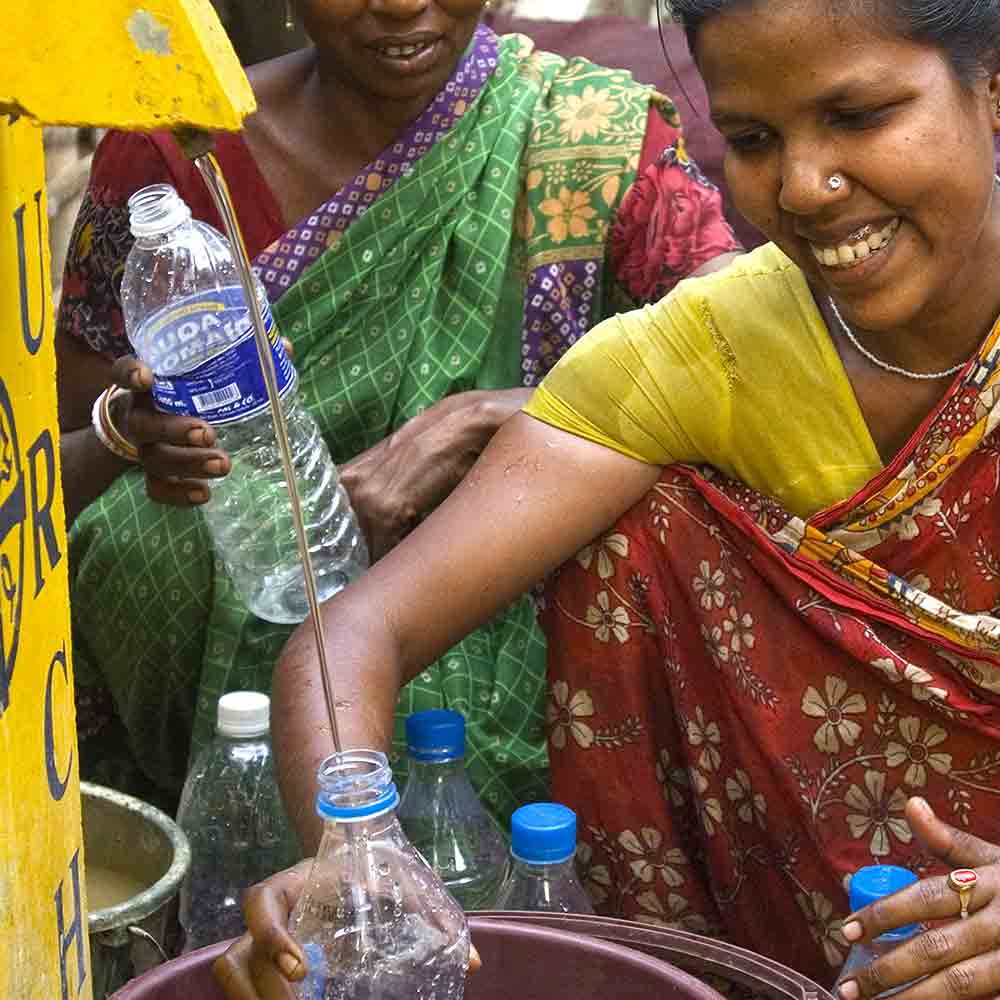 Woman filling a bottle with clean water through GFA World charity BioSand Water Filter