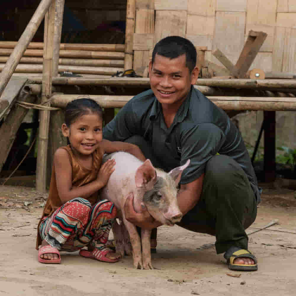A girl and her father holding an income generating gift of a pig from GFA World gift distribution