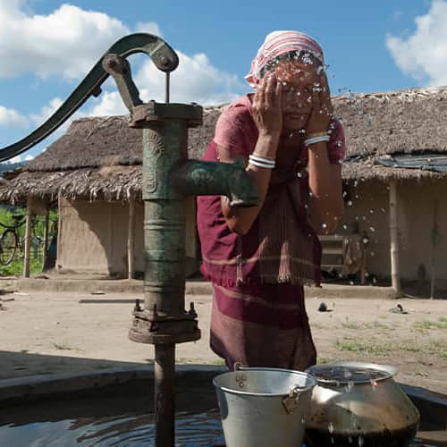 Woman washes her face with clean water through GFA World Jesus Wells