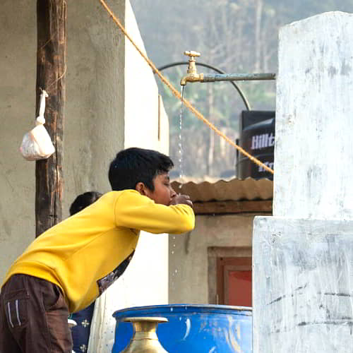 Young boy drinking clean water through GFA World Jesus Wells in Nepal