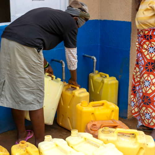 Woman from Rwanda, Africa collecting clean water through GFA World Jesus Wells
