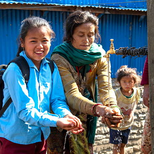 Family from Nepal washing their hands with clean water