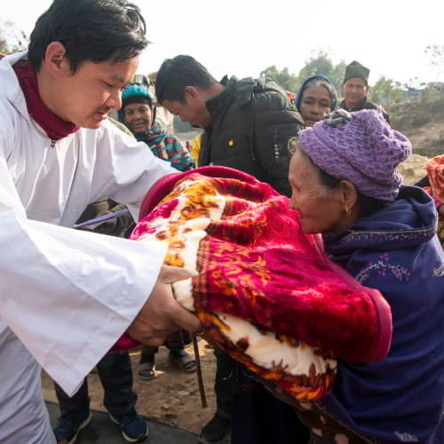 Elderly woman in poverty from Nepal receives a warm blanket through GFA World gift distribution