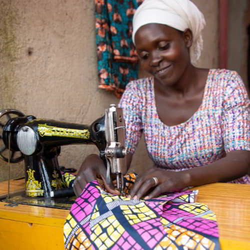 Woman learns to use a sewing machine through GFA World vocational training