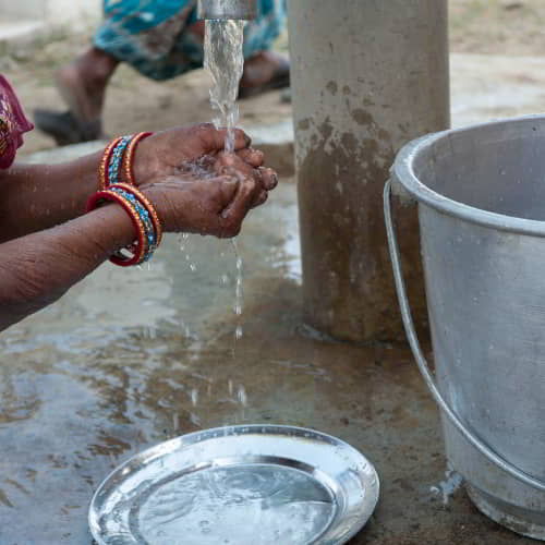Woman washes hands with clean water through GFA World Jesus Wells