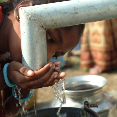 Young girl drinks clean water through one of GFA World's water solutions, Jesus Wells