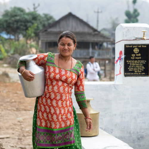 Woman carrying clean water drawn from GFA World Jesus Wells